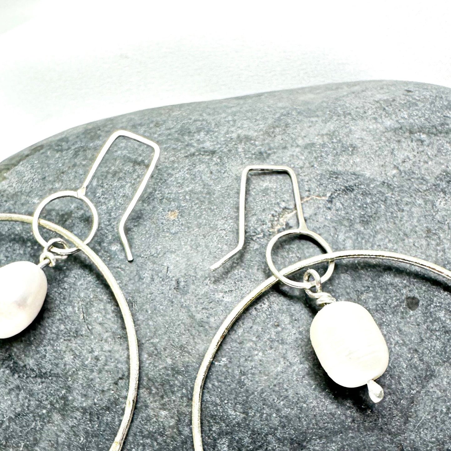 Large handmade silver hoop earrings with baroque pearl drop – minimalist sculptural jewellery by Sabine Werner