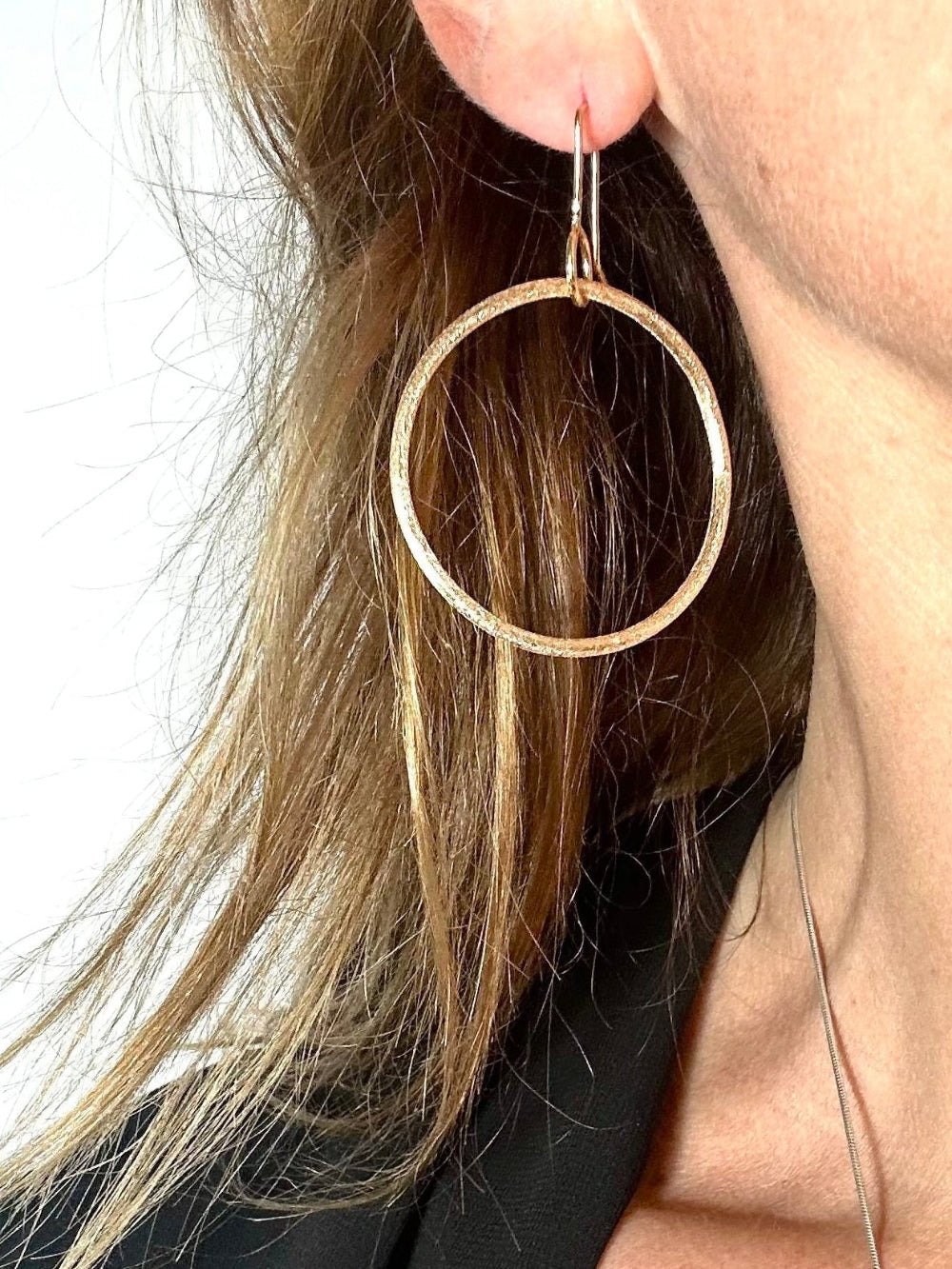 Small gold hoop earring worn, shown close on ear
