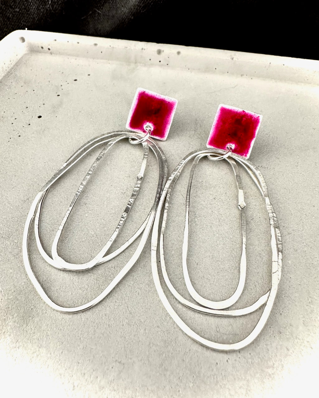 Pair of contemporary sterling silver statement earrings with multiple oval hoops and bold magenta resin square studs