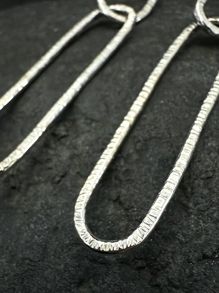 Detail of double oval link structure in hammered silver earrings