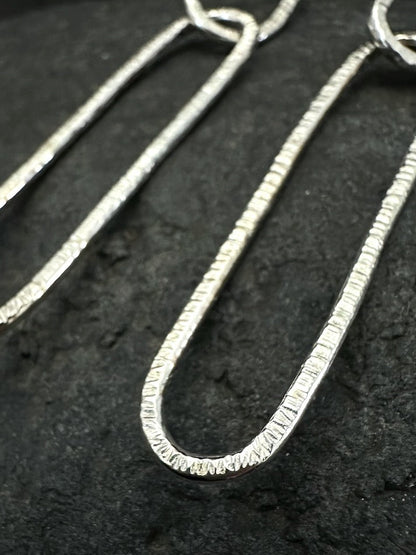 Detail of double oval link structure in hammered silver earrings