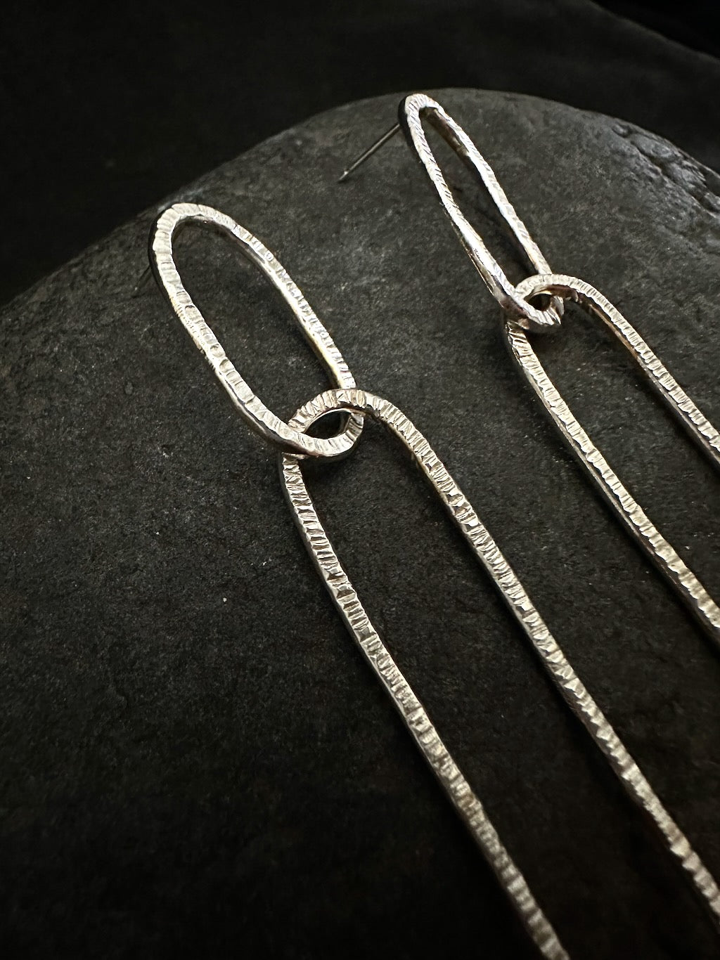 close-up of hammered texture on long oval silver earrings