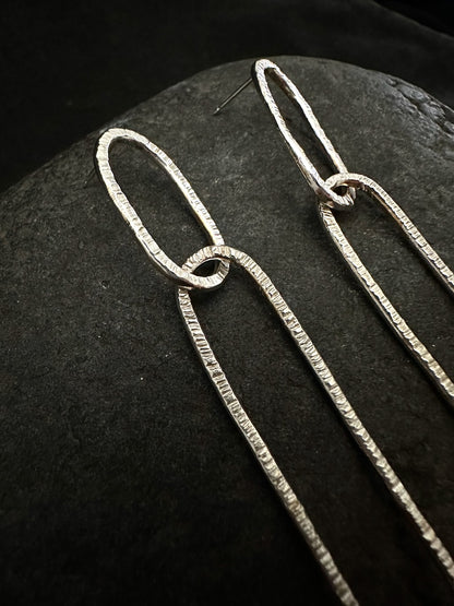 close-up of hammered texture on long oval silver earrings