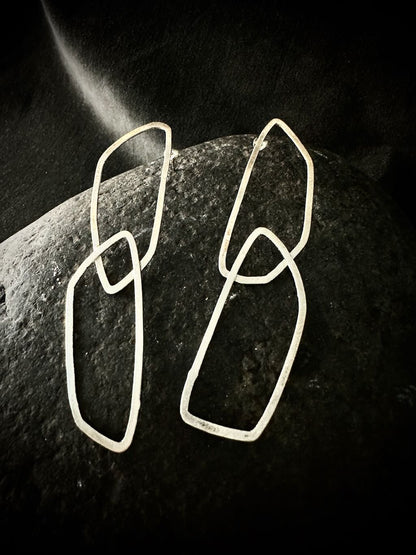 Pair of geometric sterling silver loop earrings on dark stone