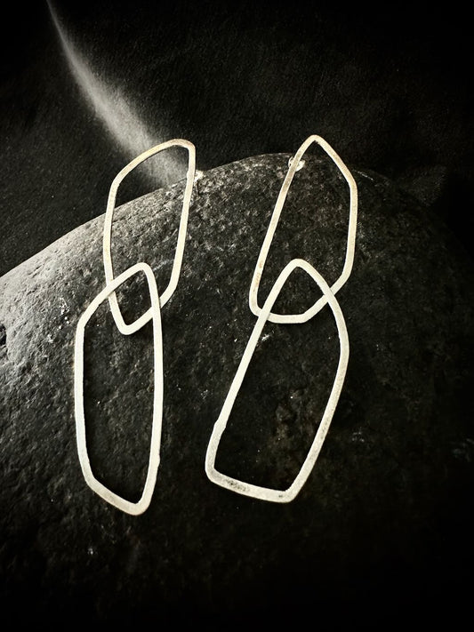 Pair of geometric sterling silver loop earrings on dark stone