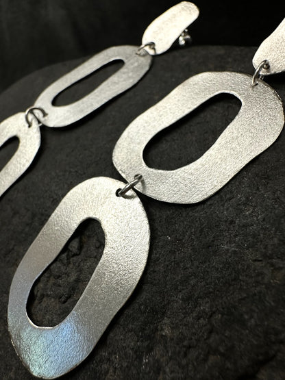 Close-up of brushed texture on organic oval silver earring shapes