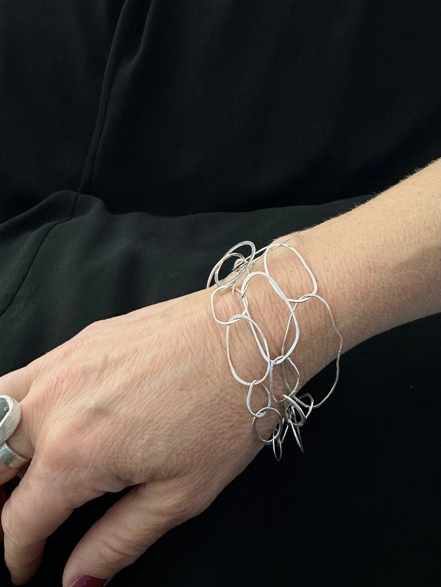Woman wearing sterling silver Loop Collection bracelet on her wrist