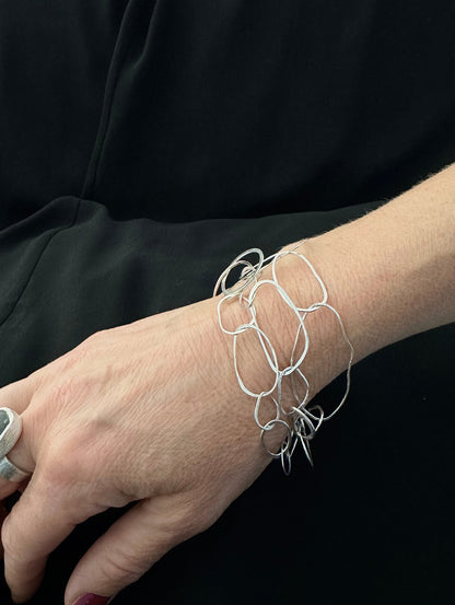 Woman wearing sterling silver Loop Collection bracelet on her wrist