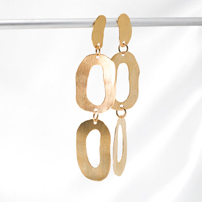 long dangly gold earrings with organic shapes