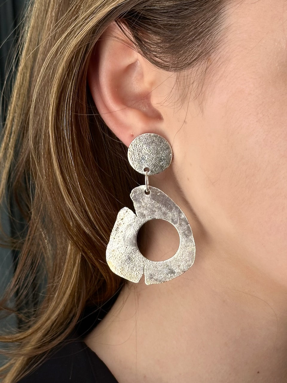 Sculptural silver hoop drop earrings worn on model. Recycled sterling silver, 62mm drop, handmade organic form, one of a kind.