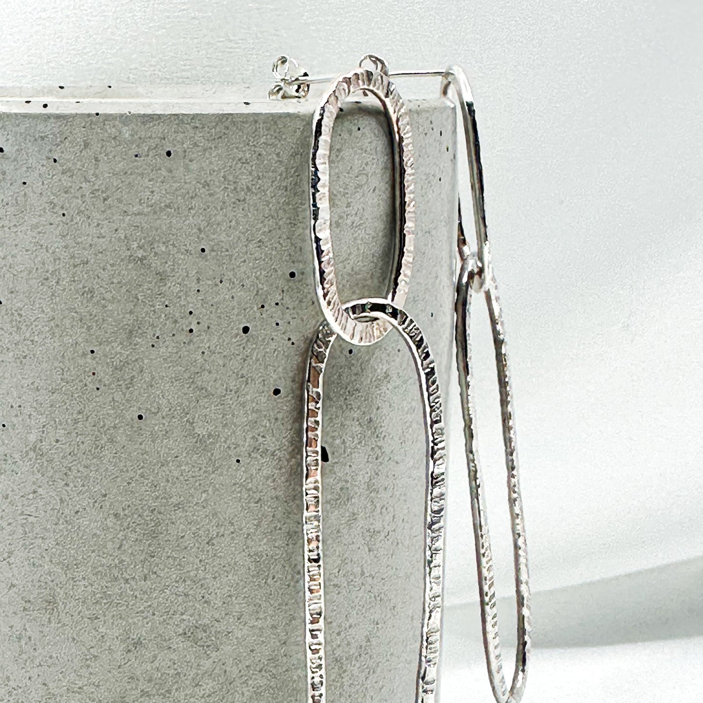 long oval dangly silver earrings in hammered structure