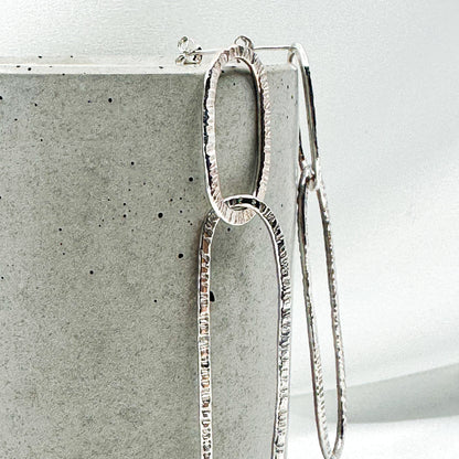 long oval dangly silver earrings in hammered structure