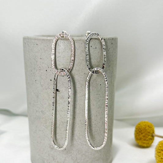 long oval dangly silver earrings in hammered structure