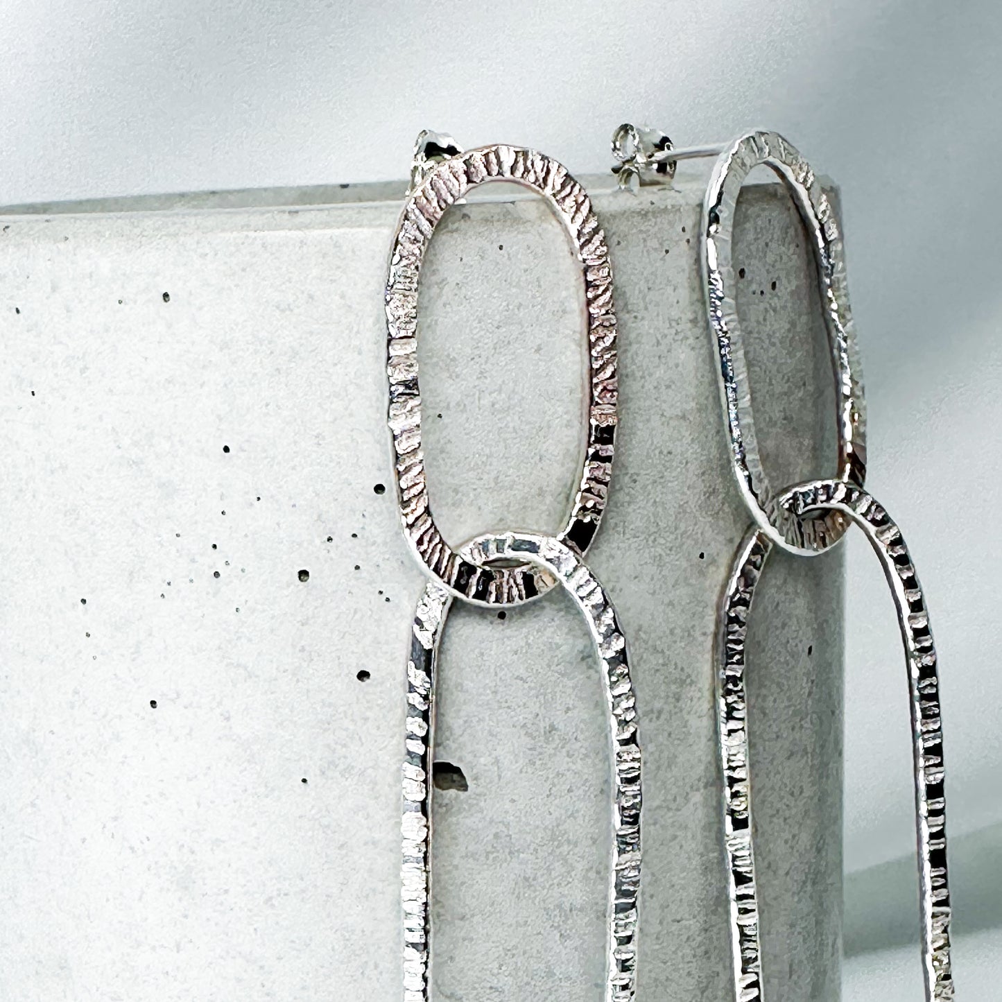long oval dangly silver earrings in hammered structure