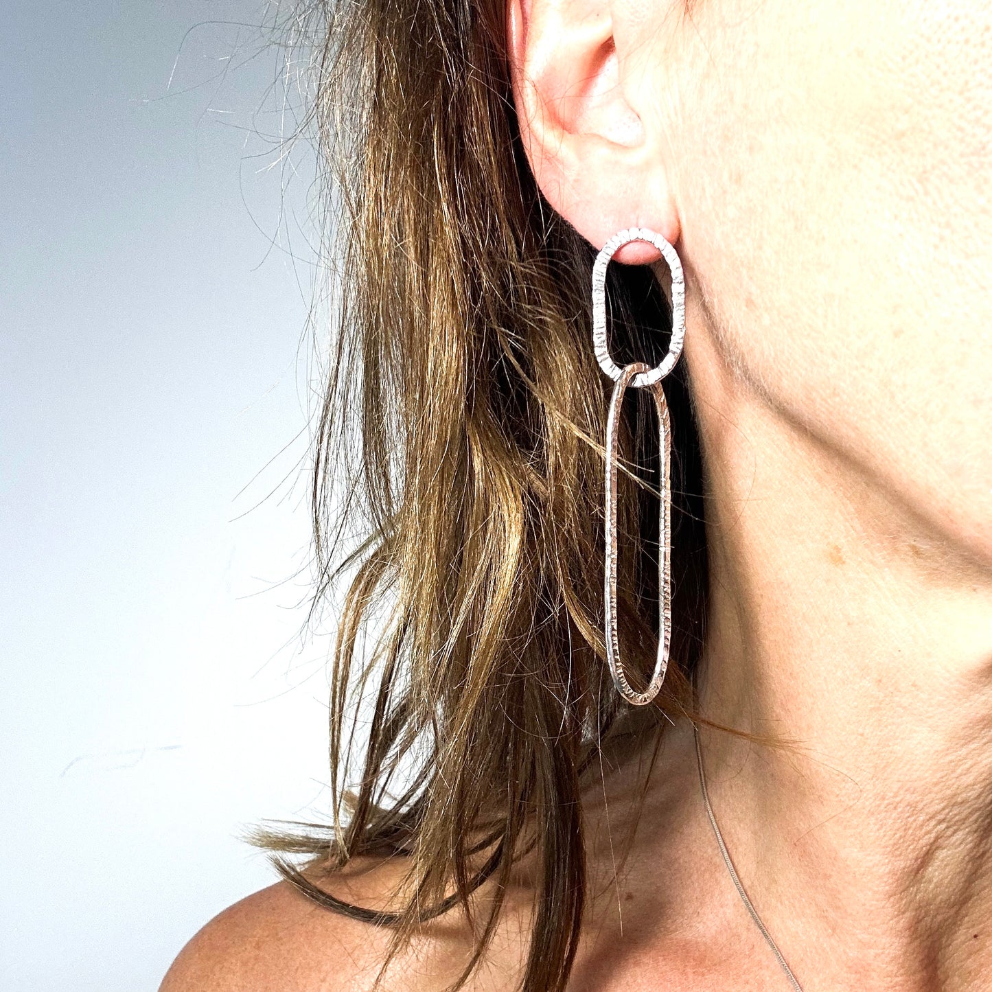 long oval dangly silver earrings in hammered structure