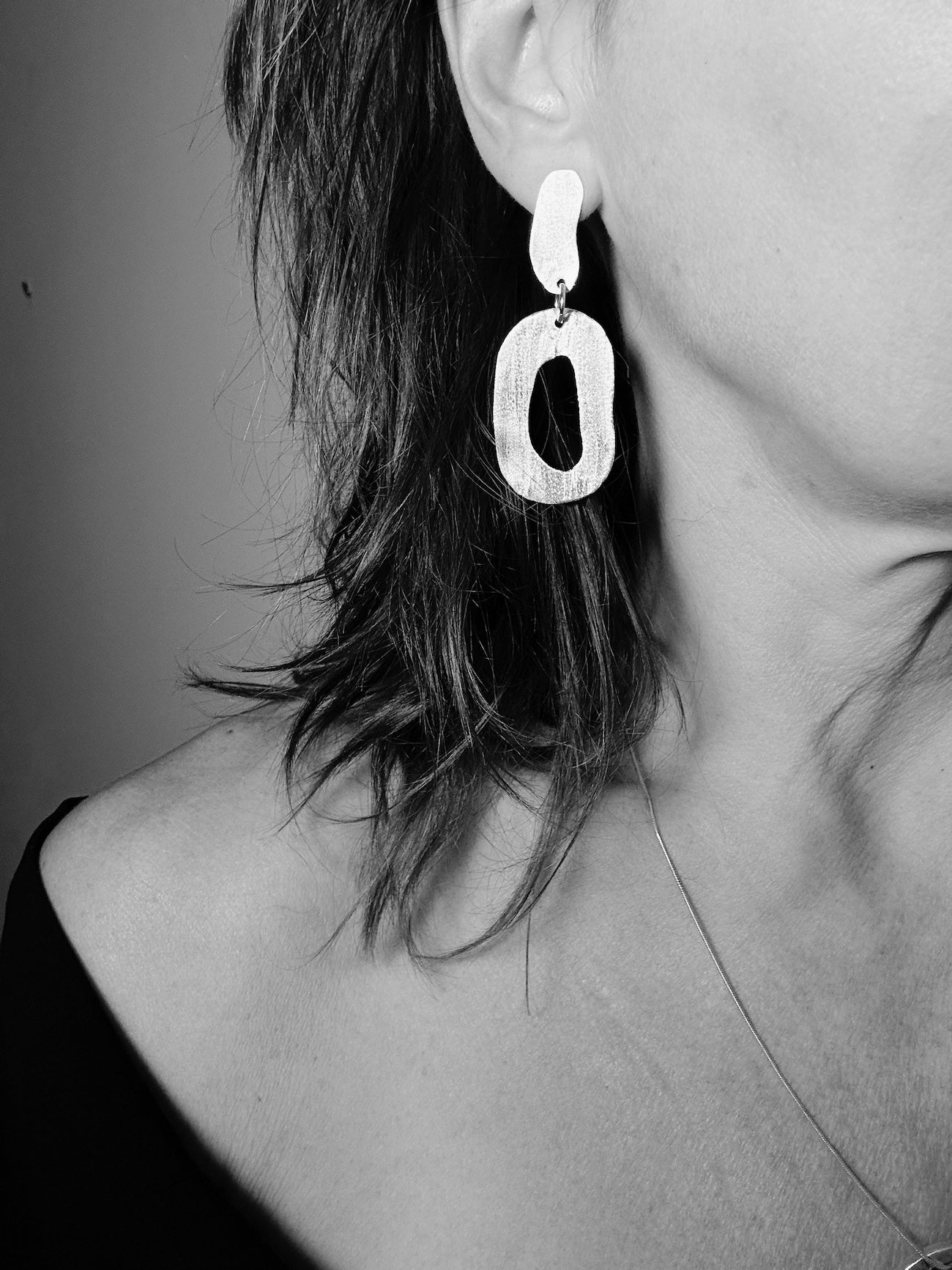 Woman wearing lightweight sterling silver drop earrings, black and white photo