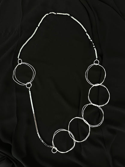Extra long statement necklace with hammered silver rings and hematite cubes laid flat