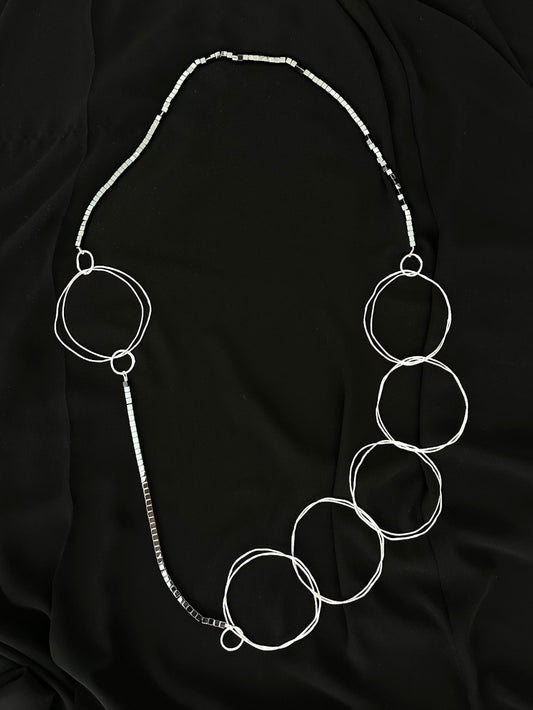 Extra long statement necklace with hammered silver rings and hematite cubes laid flat