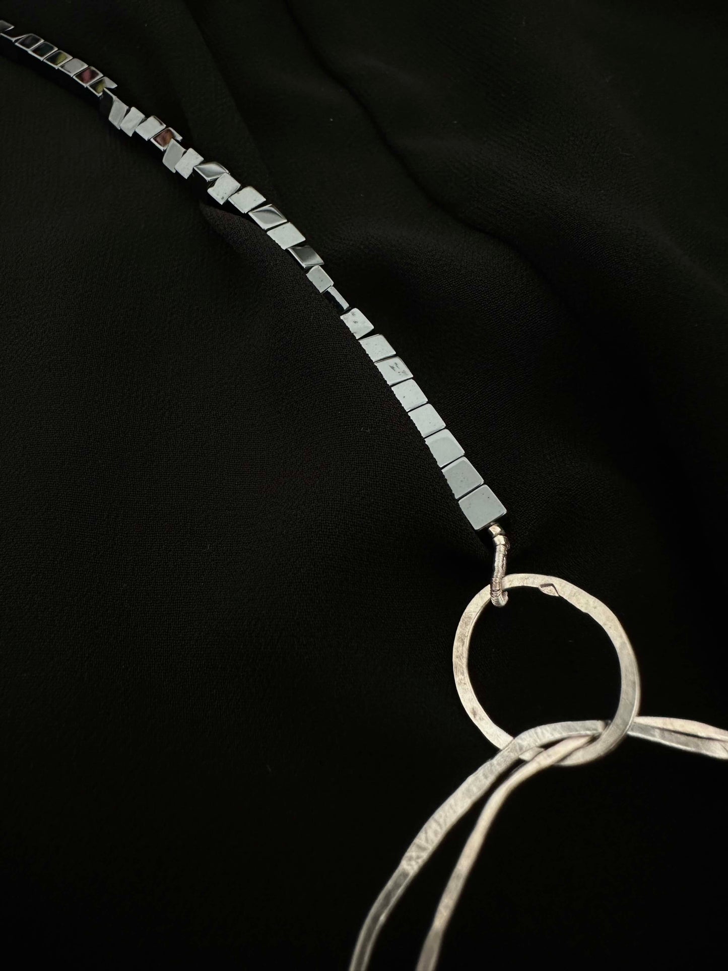 Close-up of hematite cube chain connecting to hammered silver ring