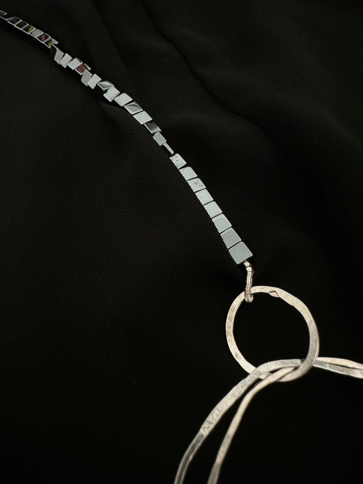 Close-up of hematite cube chain connecting to hammered silver ring