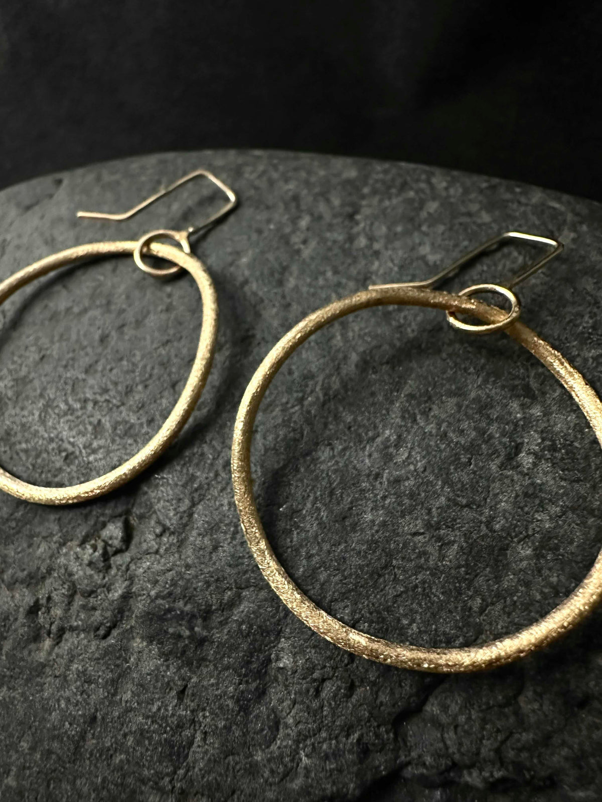 Macro detail of hand-textured surface on small gold hoop earrings