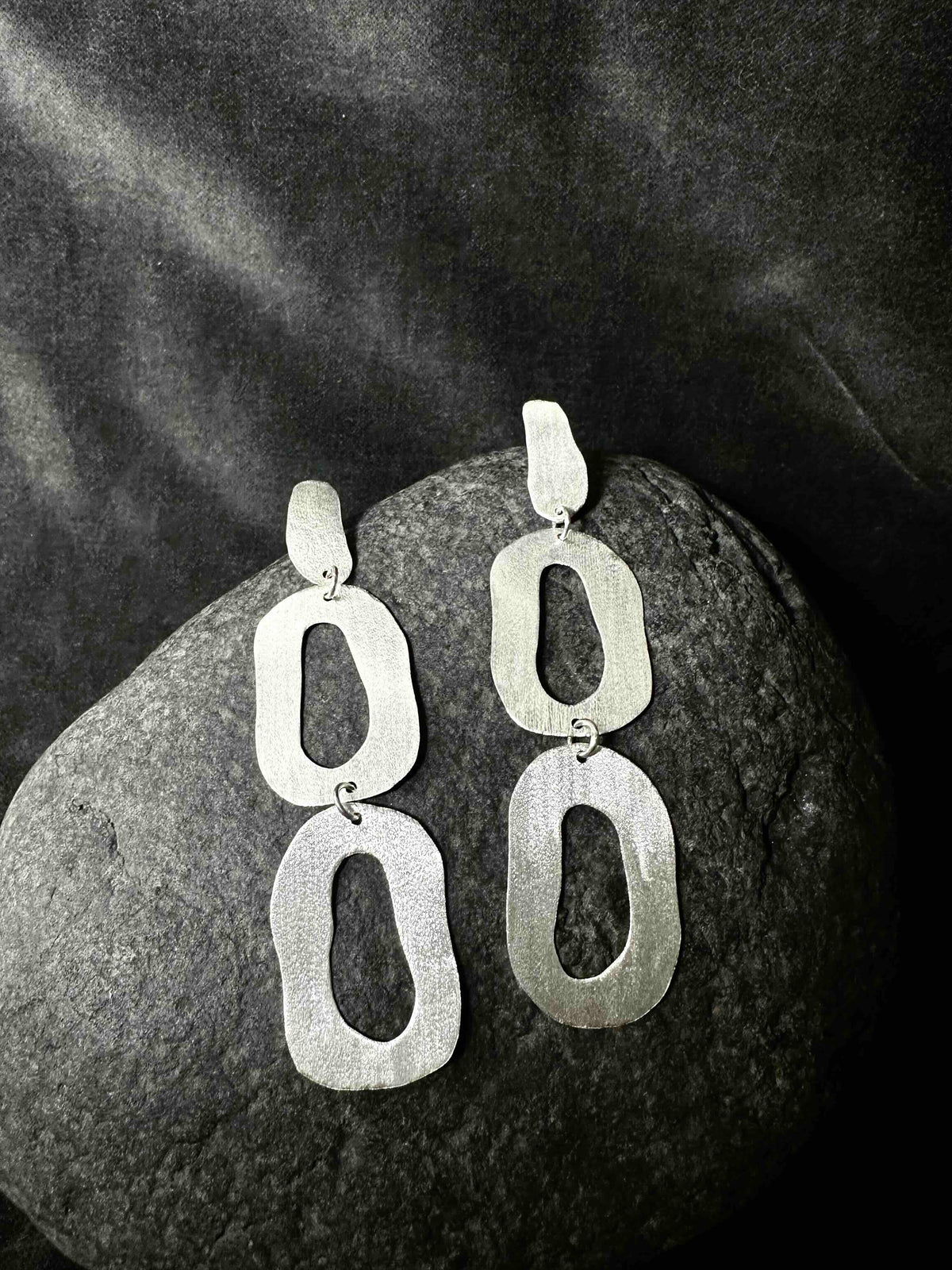 Long dangly sterling silver earrings with organic oval shapes on dark stone