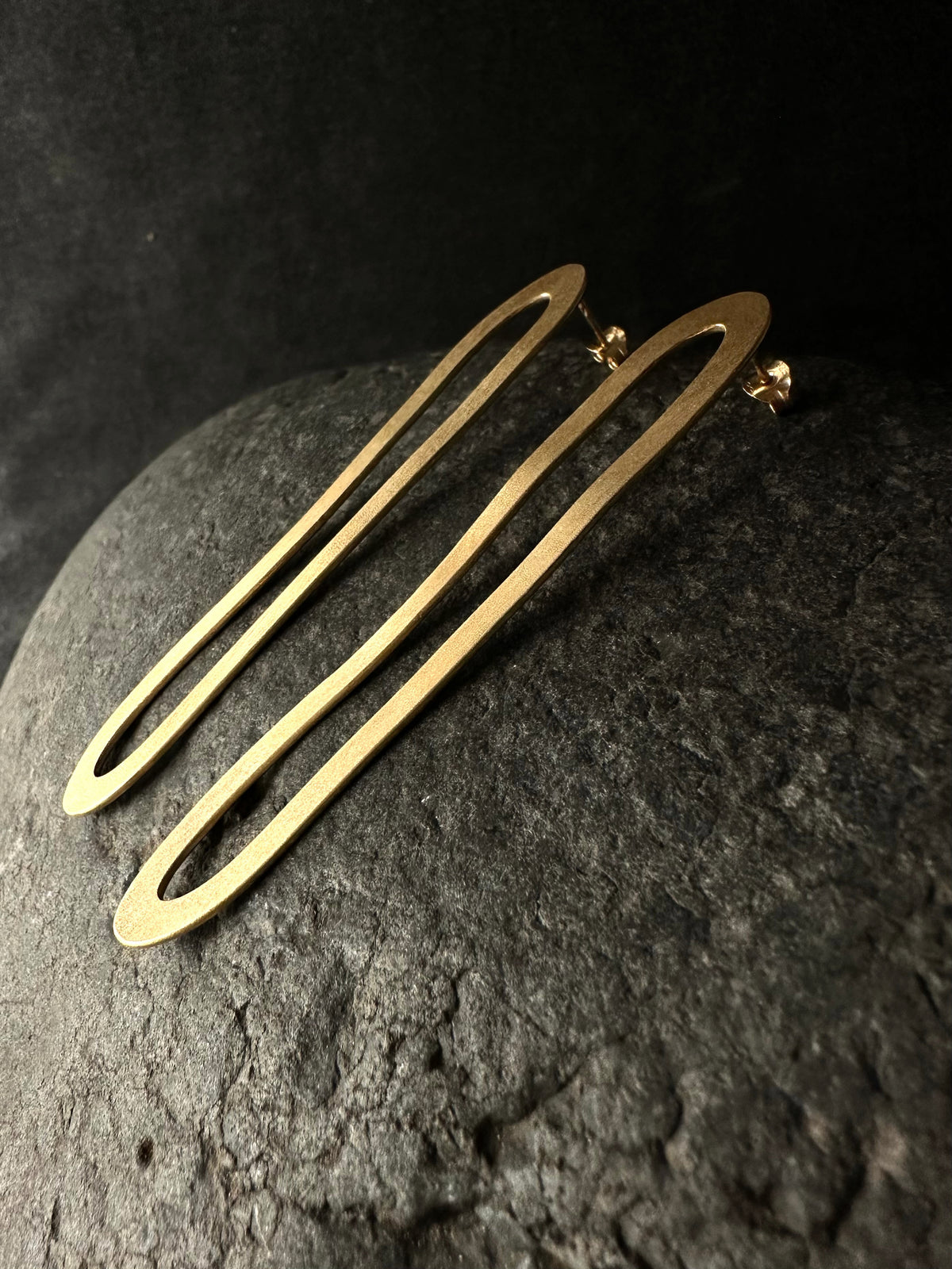 Elongated gold hoop earrings, pair standing straight-on view