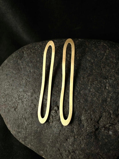 Long oval hoop earrings in gold plated sterling silver on dark stone