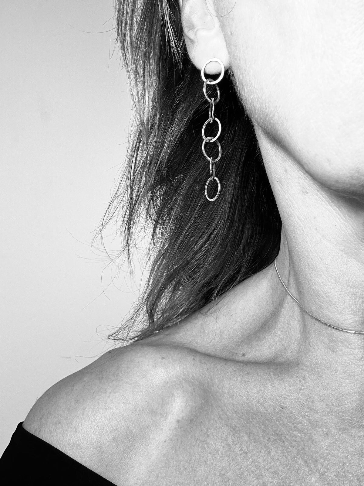 Silver loop earring worn, close-up on ear and neck
