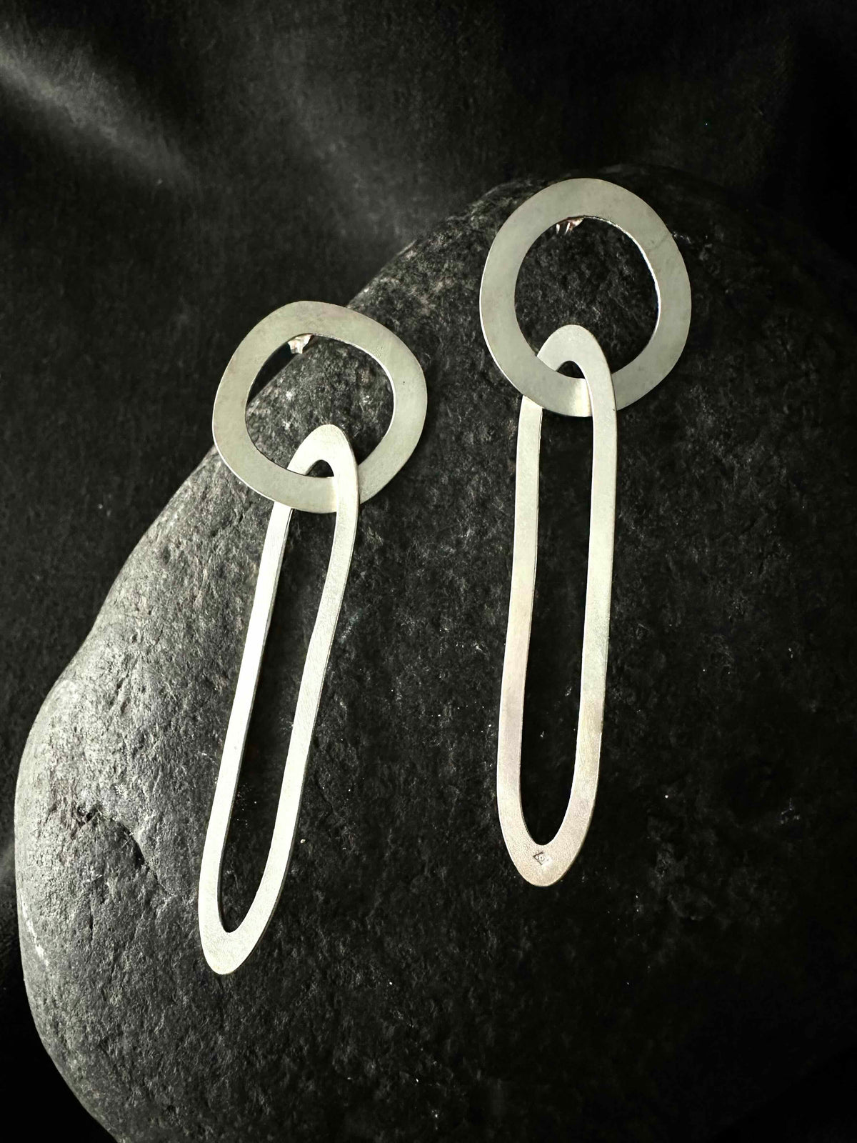 Pair of handmade geometric drop earrings on dark stone, brushed satin finish