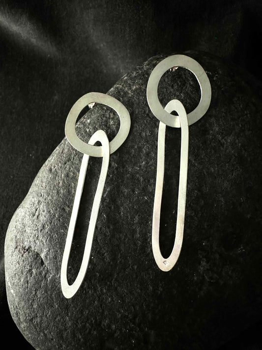 Pair of handmade geometric drop earrings on dark stone, brushed satin finish