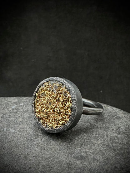 Gold druzy quartz ring in oxidised sterling silver, front view on grey stone