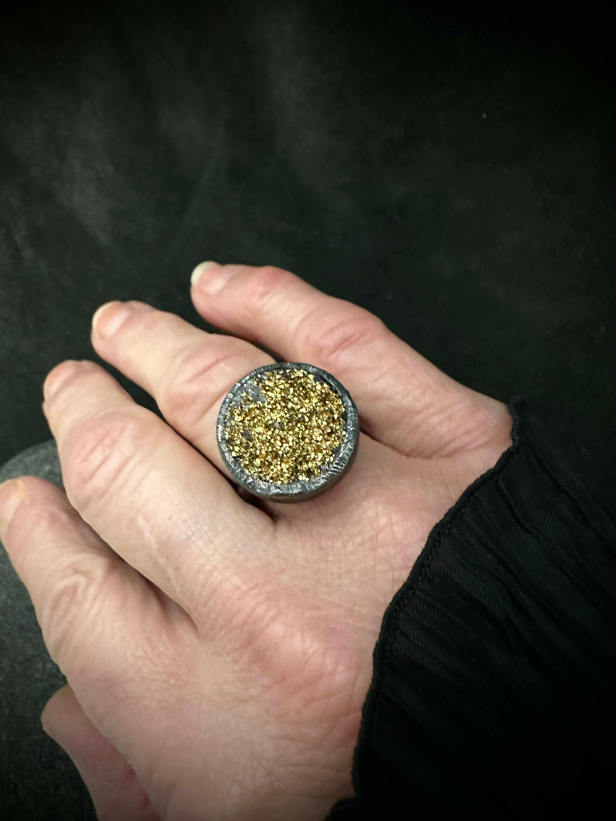 Statement druzy ring worn on hand, sparkling gold crystals in dark silver bezel