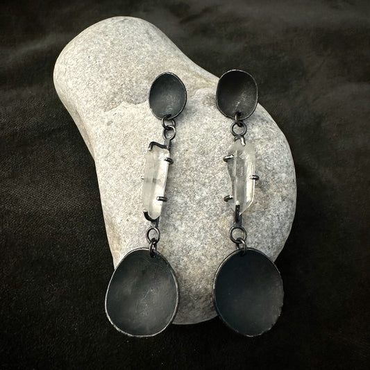 Clear quartz drop earrings in oxidised sterling silver on stone background
