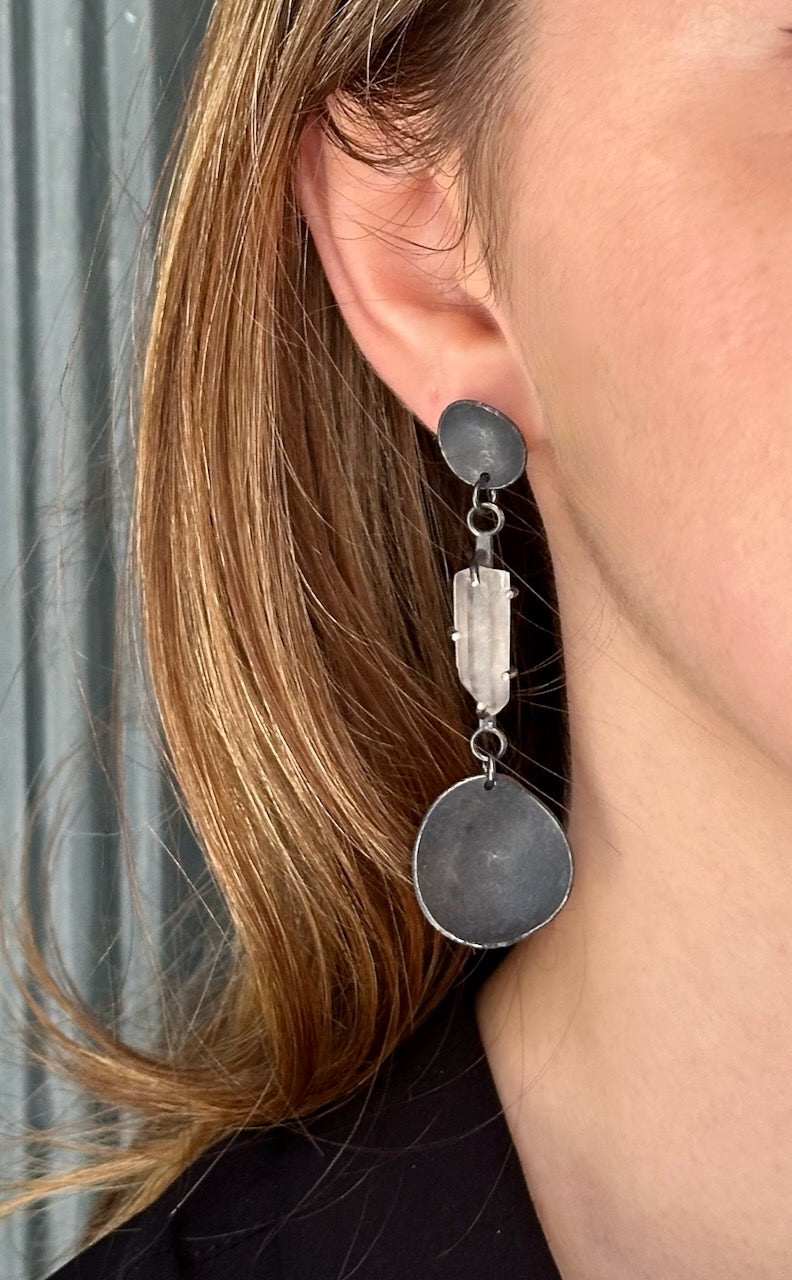 Clear quartz drop earrings in oxidised silver worn on ear, sculptural design