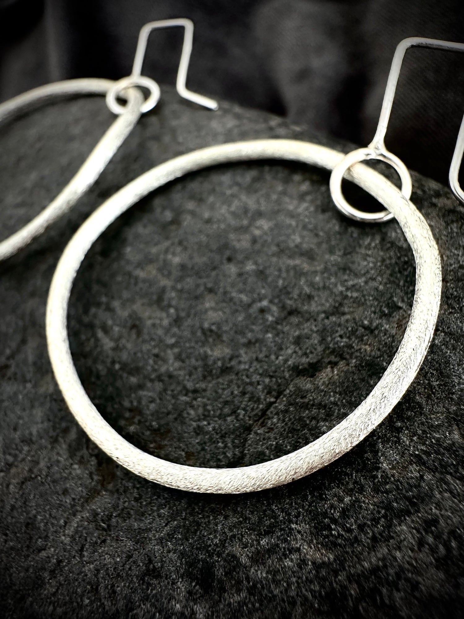 Detail shot of textured sterling silver hoop earrings showing hammered surface and ear wire