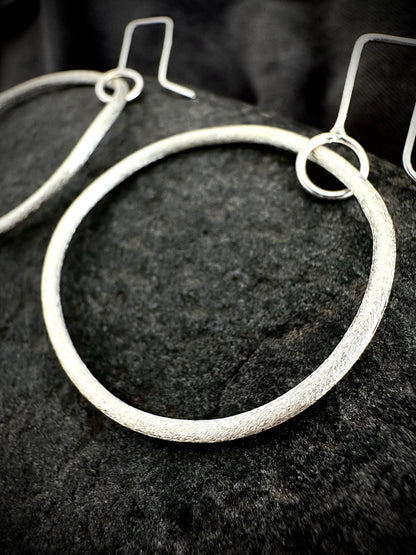 Detail shot of textured sterling silver hoop earrings showing hammered surface and ear wire