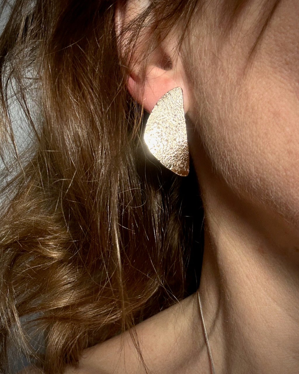 Gold plated half moon stud earrings worn on ear, textured 14ct gold plated recycled silver design