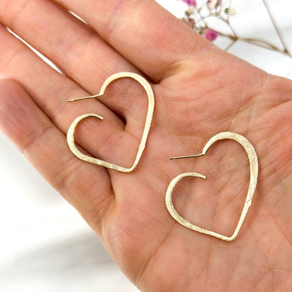 Gold-plated open heart stud earrings in 925 sterling silver, shown on hand