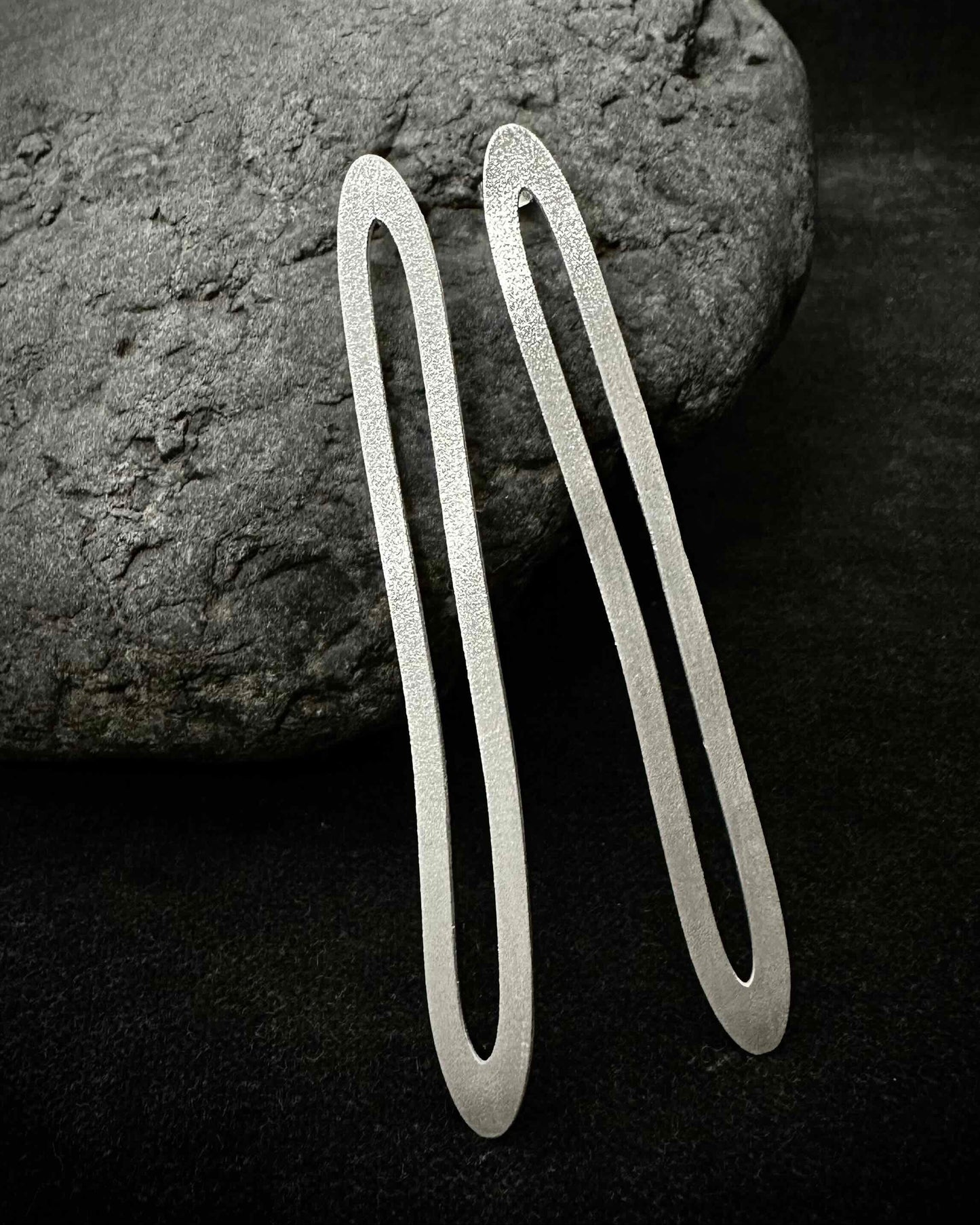 Long oval silver paperclip earrings laid on dark stone - minimalist handmade jewelry