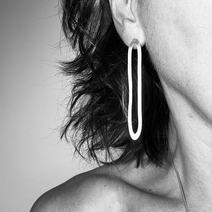 Long silver paperclip earrings standing on model