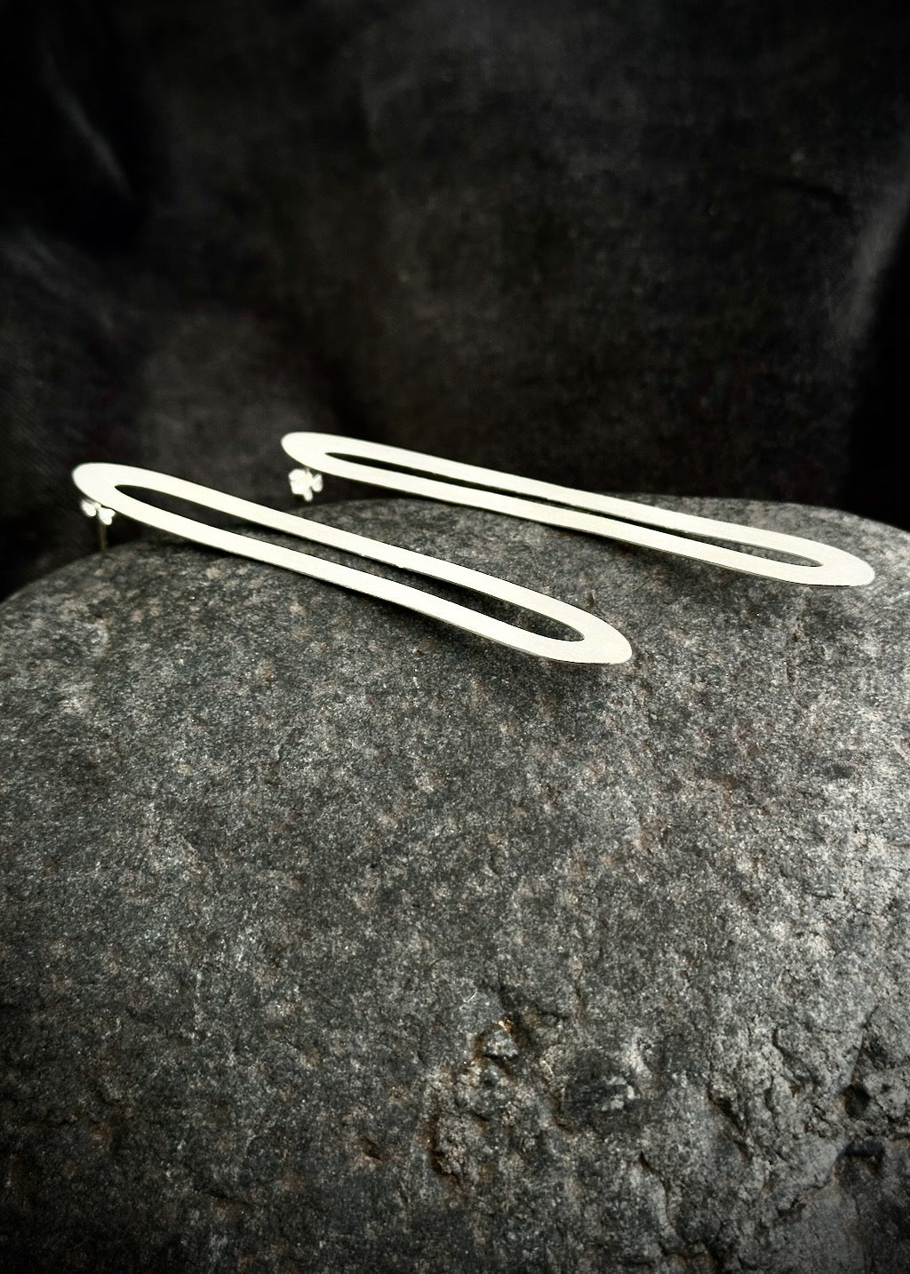 Long silver paperclip earrings standing upright against stone - brushed matte hair pin earrings