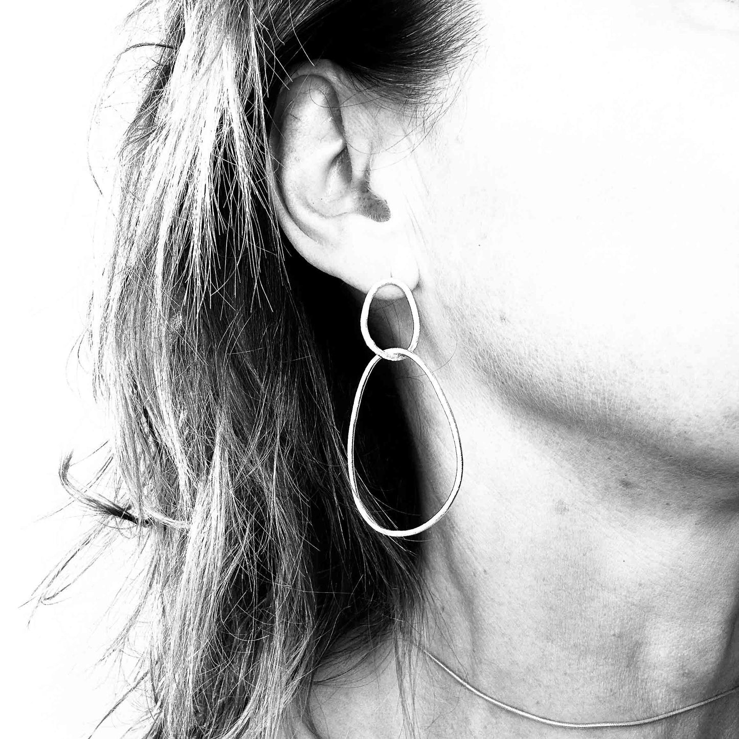 Minimalist sterling silver drop earrings with organic sculptural shapes on model