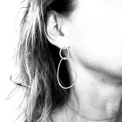 Minimalist sterling silver drop earrings with organic sculptural shapes on model