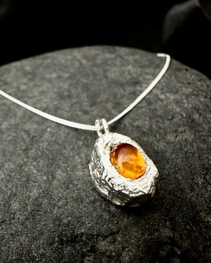 Close-up of natural amber cabochon set in textured sterling silver pendant