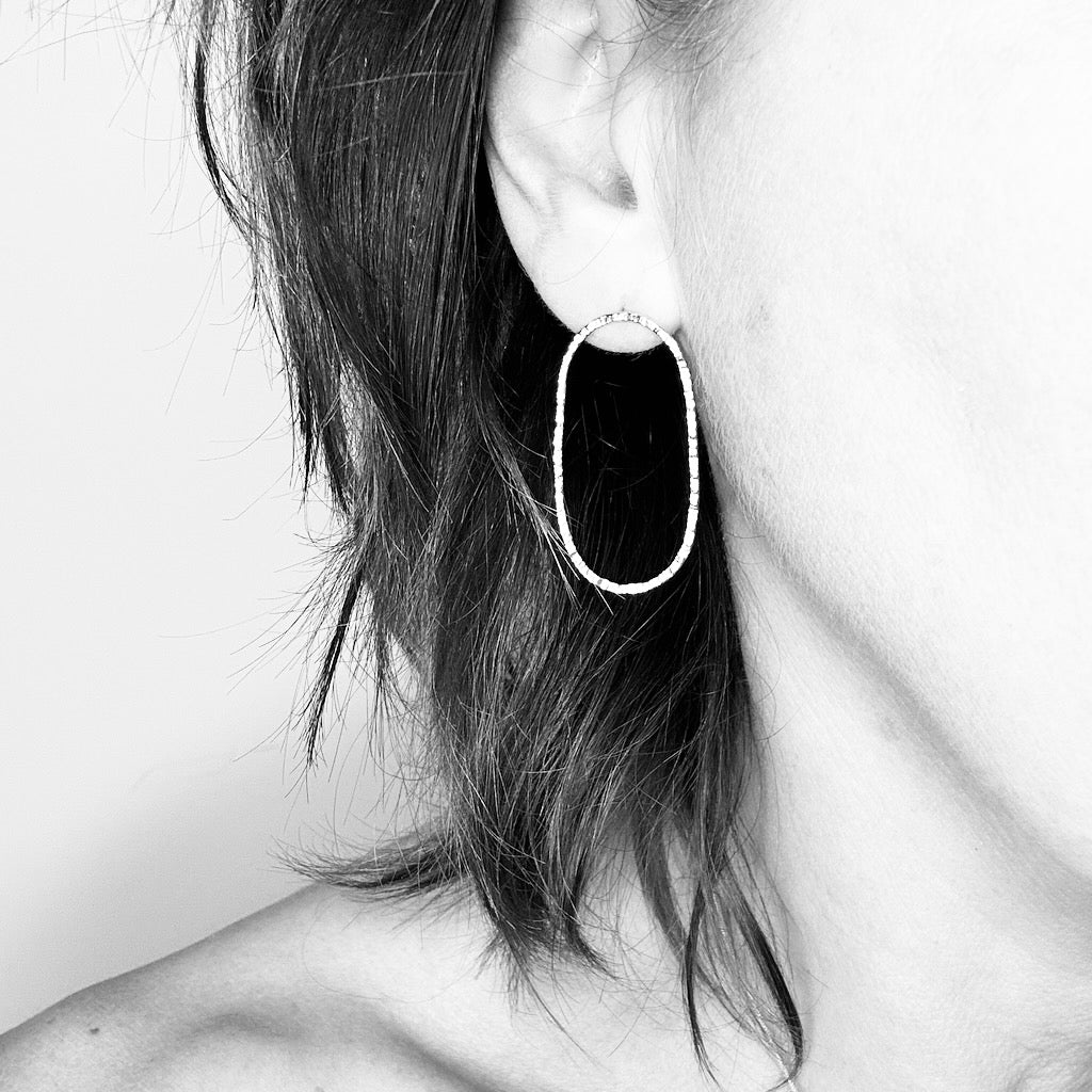 Woman wearing oval 9ct gold hoop stud earring - minimalist style