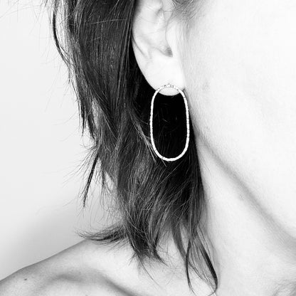 Woman wearing oval 9ct gold hoop stud earring - minimalist style