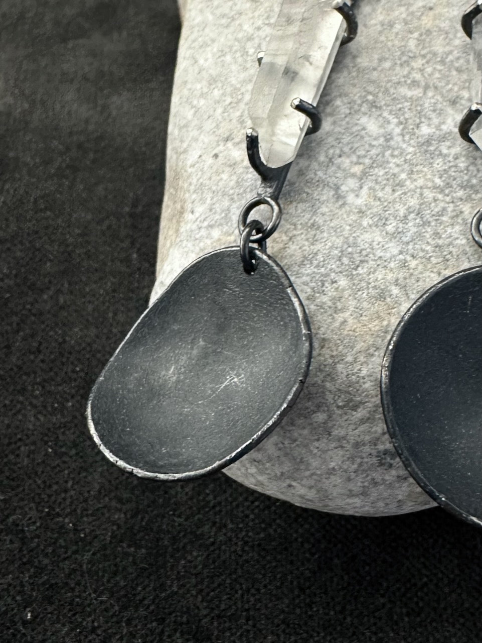 Detail of oxidised silver disc and quartz crystal in handmade drop earrings