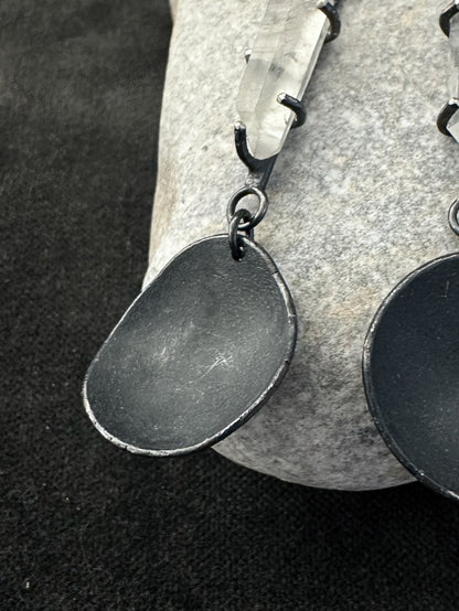 Detail of oxidised silver disc and quartz crystal in handmade drop earrings