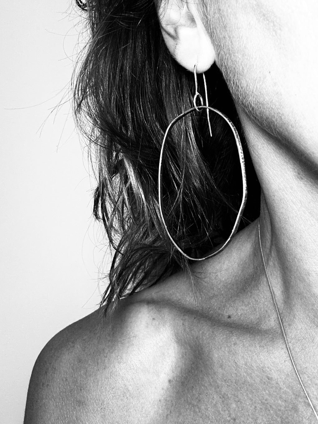 Woman wearing oxidised silver drop hoop earring - organic minimalist style